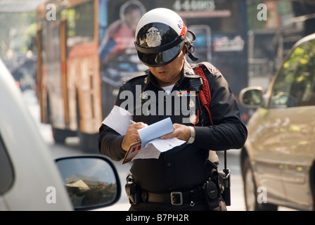 Controllo del traffico della polizia officer a scrivere una parcheggio ticket Chinatown quartiere centrale di Bangkok in Thailandia Foto Stock