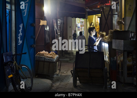 Un ragazzo offre il pane un piccolo negozio in una stretta strada del mercato in Meknes, Marocco. Foto Stock