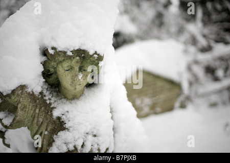 Angelo statua e pietra tombale sotto la neve nel cimitero di Nunhead Foto Stock