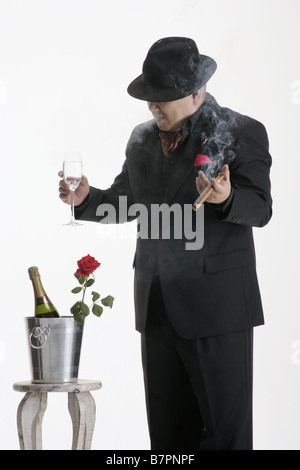 Un uomo vestito in mano un bicchiere Foto Stock