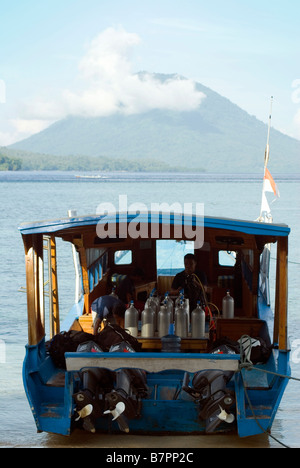 Una barca di immersione si prepara per un'alba raid su i misteri di Bunaken reef, sotto l'ombra di Manado Tua vulcano Foto Stock