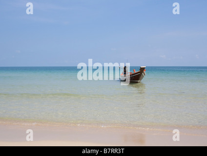 Di una barca dalla coda lunga siede sulle acque cristalline di Ao Thong Nai Pan Noi beach Koh Phangan Thailandia sotto un cielo blu Foto Stock