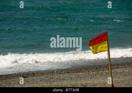 Bandiera rossa e gialla sulla spiaggia di RNLI su una spiaggia del Regno Unito che indica che è sicuro nuotare. Foto Stock