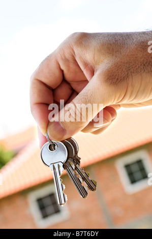 S Man mano che tiene i tasti con una casa in costruzione in background Foto Stock