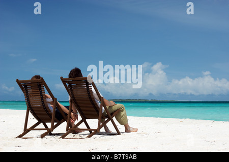 Coppia giovane sulla spiaggia seduta nel lettino e gode di vista oceano Foto Stock