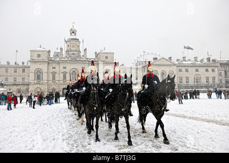 Cavalleria della famiglia in sella a neve attraverso Horseguards Parade di dazi a Buckingham Palace dopo un cambio della guardia Foto Stock