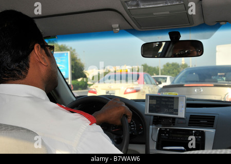 Vista interna ravvicinata sul retro del tassista di Dubai la mano del conducente sul volante che guida dall'aeroporto è bloccata in posizione Ingorghi di traffico Emirati Arabi Uniti UAE Foto Stock