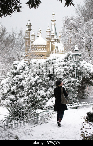 Giovane donna cammina attraverso la coperta di neve giardini del Royal Pavilion in Brighton la mattina presto. Foto Stock