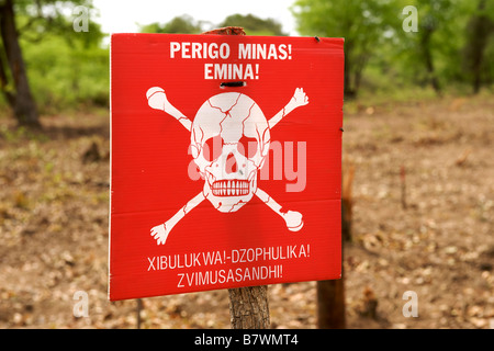 Cranio e crossbones e 'drabbia mine' avviso in portoghese e shangaan su un segno sul bordo di un campo minato in Mozambico. Foto Stock