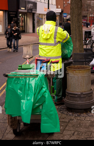 Pulitore di via lo svuotamento di bin in Hounslow High Street, Middlesex, Regno Unito. Foto Stock