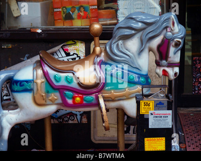 Colorate, invecchiamento a gettone di equitazione o giostra cavallo macchina per bambini su una strada della citta'. Foto Stock