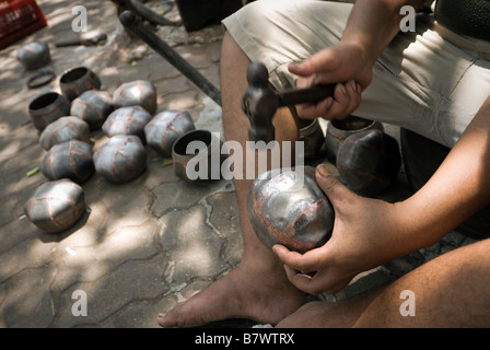 Dettaglio di artigiano battendo in ALMS bocce in ciotola monaci villaggio divieto Soi Baat centrale di Bangkok in Thailandia Foto Stock