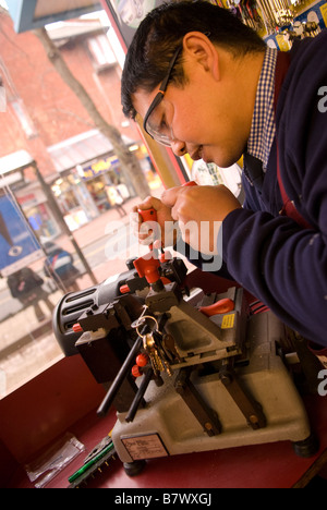 Membro del personale chiavi di taglio in Timpsons, High Street, Hounslow, Middlesex, Regno Unito. Foto Stock