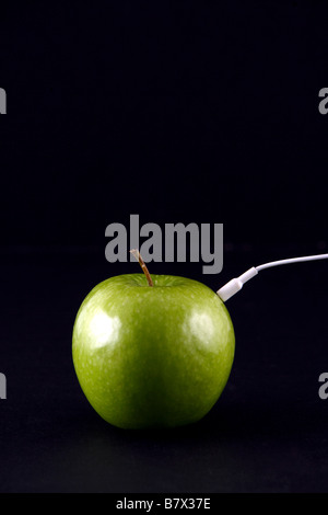 Una mela verde con cuffie in studio Foto Stock