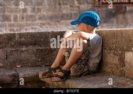 Un piccolo ragazzo seduto su un banco di lavoro Foto Stock