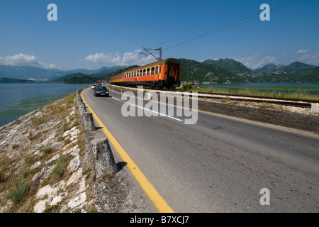 Treno e Auto andando oltre la diga nel lago di Skadar, Montenegro Foto Stock