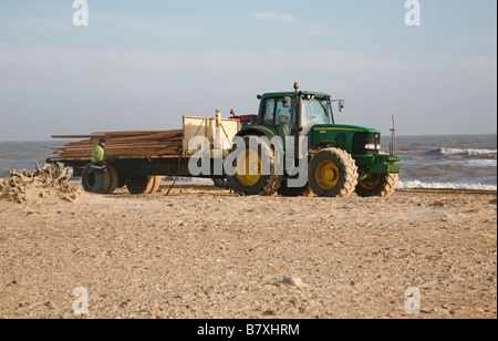 Il trattore trasporto legname recuperati lavato fino di spiaggia da colpite nave cargo Suffolk Inghilterra Gennaio 2009 Foto Stock