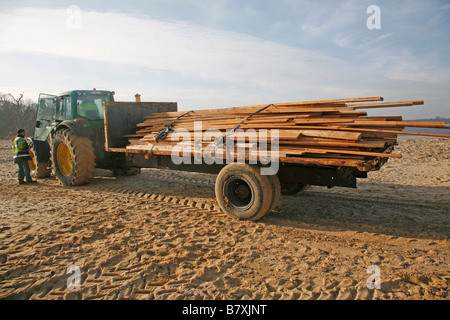 Il trattore trasporto legname recuperati lavato fino sulla spiaggia colpita dalla nave cargo Suffolk Inghilterra Gennaio 2009 Foto Stock