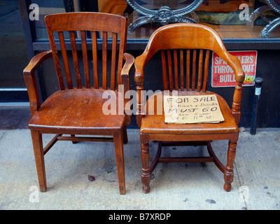 Due vecchie sedie di legno su un marciapiede in città tenendo un cartone scritti a mano per la vendita di segno. Foto Stock