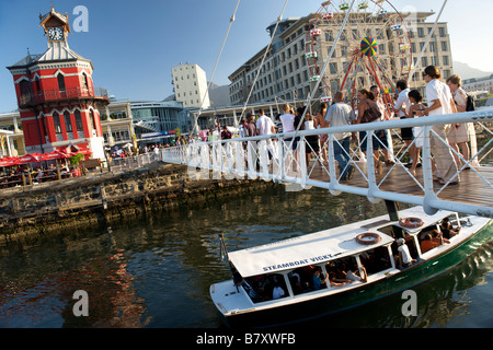 Piccola barca passando sotto il ponte pedonale di fronte alla torre dell orologio a Cape Town il Victoria and Alfred Waterfront. Foto Stock