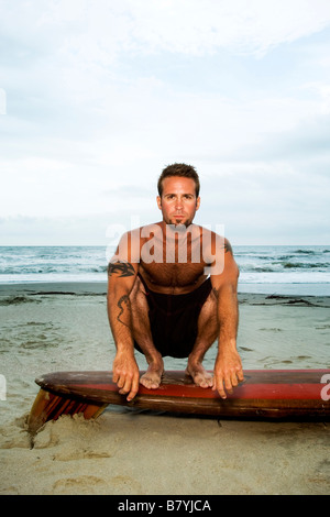 Surfer a beach seduto sulla tavola da surf, ritratto Foto Stock