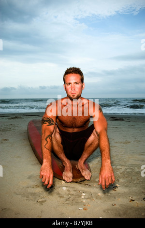 Surfer a beach seduto sulla tavola da surf, ritratto Foto Stock