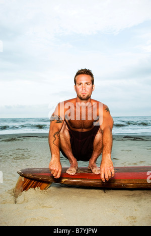 Surfer a beach seduto sulla tavola da surf, ritratto Foto Stock