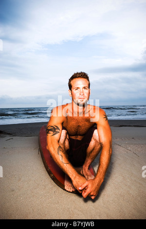 Surfer a beach seduto sulla tavola da surf, ritratto Foto Stock