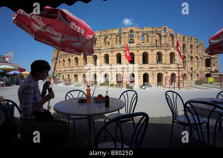 Un toursist ha un drink in un bar di fronte all'Anfiteatro Romano / Coliseum. El Jem, Tunisia. Foto Stock