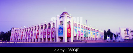 Serata panoramica colpo di un dell era sovietica edificio decorato con colorati Kygyz banner su Bishkek centrale dell'Ala troppo square. Foto Stock