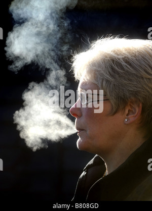 Donna soffiando il fumo di sigaretta dalla sua bocca Foto Stock