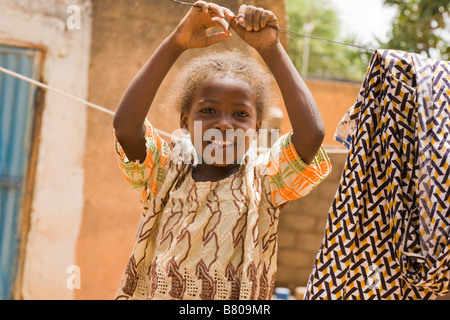 Giovane ragazza Fulani gioca sulla linea bucato nella sua famiglia del composto in Ouagadougou, Burkina Faso. Foto Stock