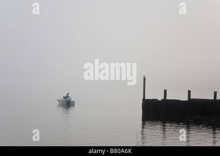 L uomo nella piccola barca derive nella nebbia lasciando il lancio in barca a Crooked River State Park vicino a St Marys, GEORGIA, STATI UNITI D'AMERICA Foto Stock