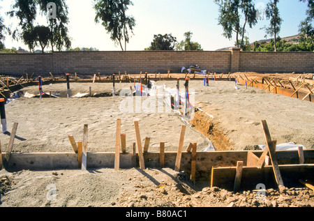 Trincee tagliate nella terra riempita con forme di legno per gettare fondamenta in calcestruzzo per la costruzione di Foto Stock