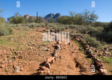 Un sentiero sterrato delineato dalle rocce porta nel profondo la superstizione la gamma della montagna nel deserto dell'Arizona. Foto Stock