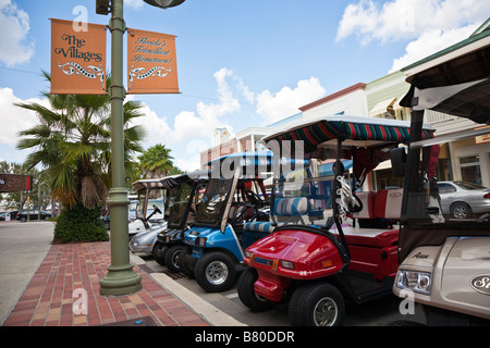 Carrelli da golf parcheggiate lungo la strada principale nei villaggi la comunità di pensione nella Florida Centrale, STATI UNITI D'AMERICA Foto Stock