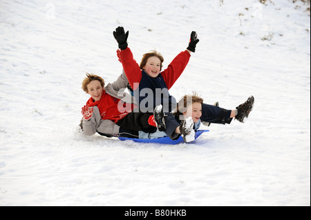 Tre ragazzi in slitta nella neve inverno 2009 giocando DIVERTENTE FOTO DI DAVID BAGNALL Foto Stock