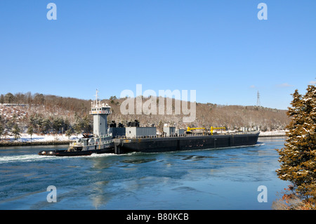 Grigio rimorchiatore spinge scafo nero barge attraverso il canale di Cape Cod in inverno Foto Stock