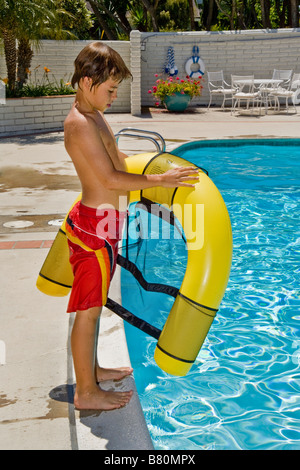 A dieci anni di vecchio ragazzo prepara un galleggiante giallo prima di entrare in una piscina a Laguna Niguel CA Foto Stock