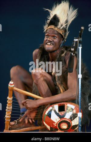 Musicista africano della Costa d'Avorio in Africa Occidentale che suona l'Arpa cetra, eseguire sul palco in costume tradizionale Foto Stock