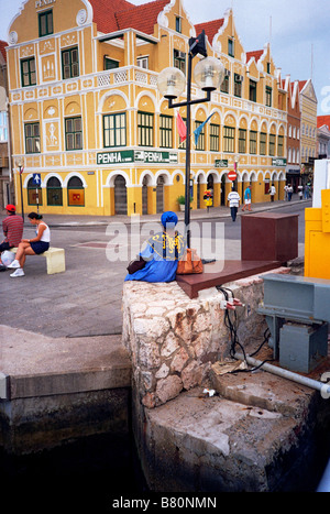 Una luminosa vestito donna in attesa di un autobus nel centro della città in Curacao, Antille Neltherlands Foto Stock