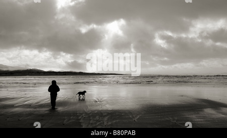 Un uomo a piedi il suo cane su un Oregon spiaggia con il suo cane al tramonto. Lincoln City, Oregon, Stati Uniti d'America. Foto Stock
