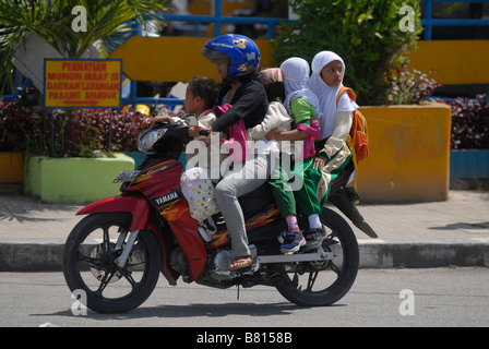 Motociclo con una donna che indossa un casco e quattro figli senza casco di Biak, Indonesia. Foto Stock