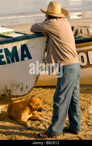 Messico SINOLA MEMBRO MAZATLAN pescatore locale con cane in appoggio sulla sua barca da pesca. Old Mazatlan Foto Stock
