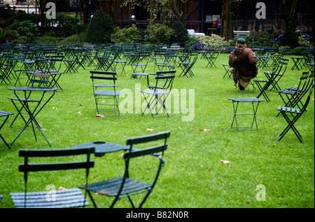 Lonely Uomo seduto tra un campo di sedie vuote in Bryant Park di New York City, NY USA (per solo uso editoriale) Foto Stock