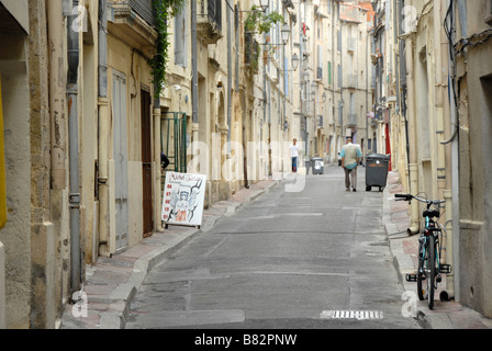 Bike appoggiata contro un muro di casa, la gente in distanza, stradina nel centro storico della città vecchia di Montpellier, Francia, Europa Foto Stock