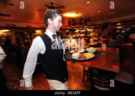 Un cameriere si precipita con un vassoio di cibo in un ristorante affollato Bradford West Yorkshire Foto Stock