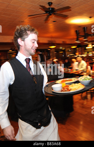 Un cameriere si precipita con un vassoio di cibo in un ristorante affollato Bradford West Yorkshire Foto Stock