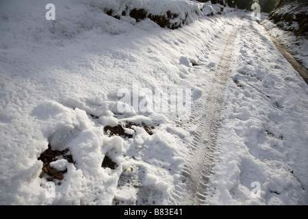 Pneumatico auto tracce nella neve su un bosco LANE, Surrey, Inghilterra. Foto Stock