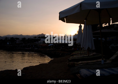 Sedie a sdraio allineate sul fronte spiaggia area di Masbat al tramonto nel Sinai resort di Dahab in Egitto Foto Stock